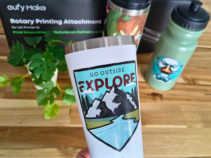 Zu sehen ist mit dem eufyMake E1 ein bedruckter Becher im Vordergrund, sowie weitere bedruckte Muster.