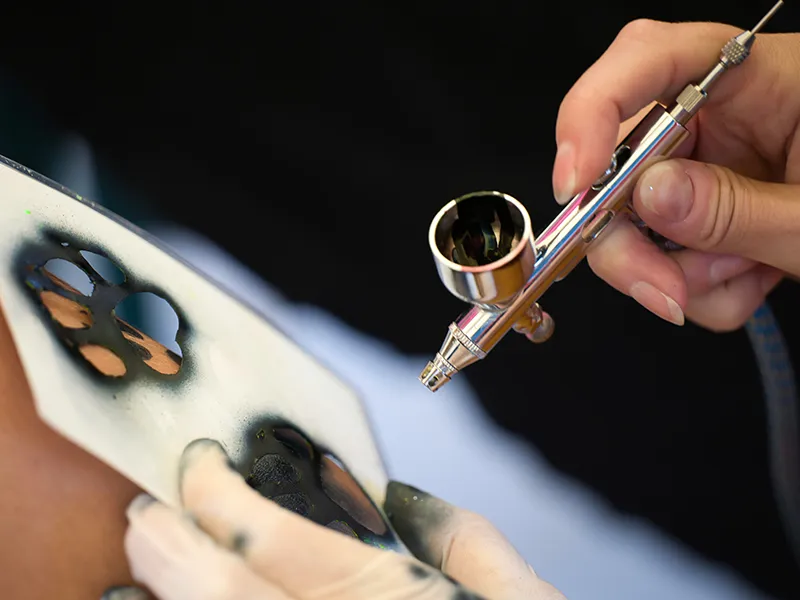 Eine Airbrush Schablone wird verwendet um ein Pfoten Motiv aufzusprühen.