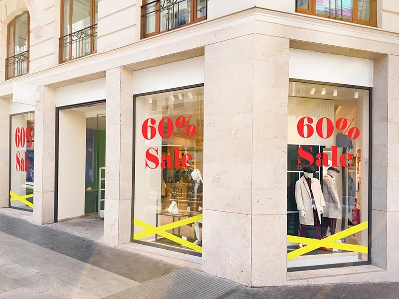 Schaufenster eines Modegeschäfts sind mit Sale Beschriftungen beklebt.