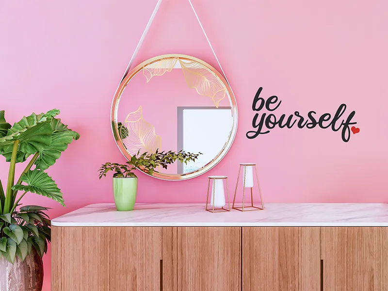 "Be yourself" ist als Schriftzug auf einer rosa Wand geklebt.